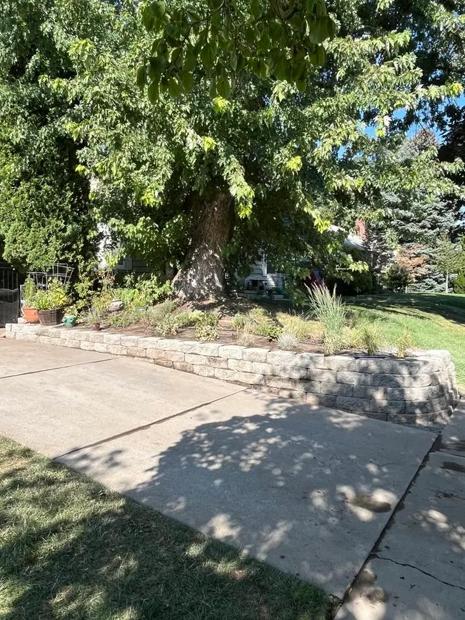 Block retaining wall with plantings beside a sidewalk